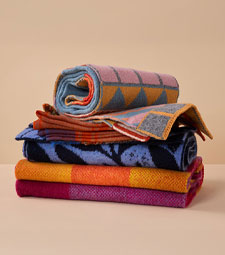 Stacked woollen scarves in various colourful patterns.